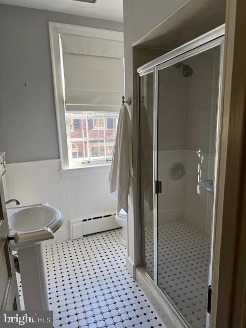 bathroom with toilet, a shower with shower door, tile patterned flooring, and a baseboard heating unit