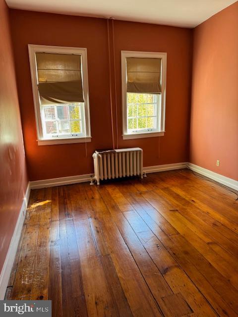 empty room with radiator heating unit and hardwood / wood-style flooring