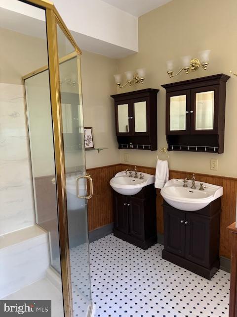 bathroom with vanity, wooden walls, and a shower with shower door