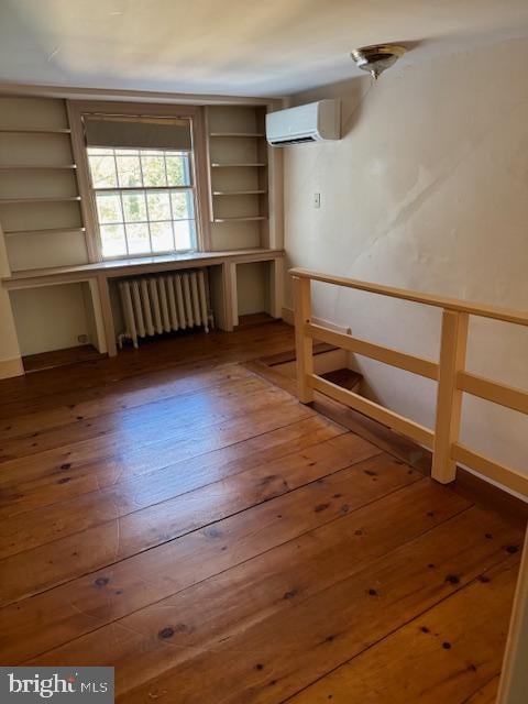 basement featuring radiator, hardwood / wood-style flooring, and a wall mounted AC