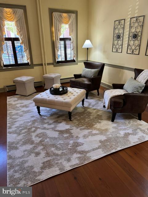 living area with wood-type flooring and baseboard heating