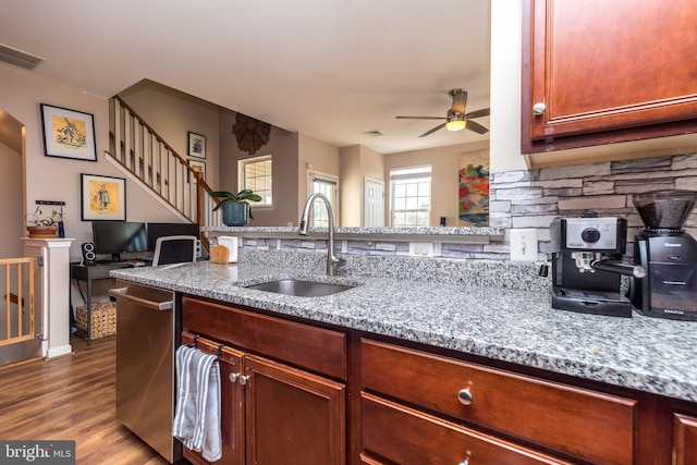 kitchen featuring light stone counters, stainless steel dishwasher, ceiling fan, sink, and wood-type flooring