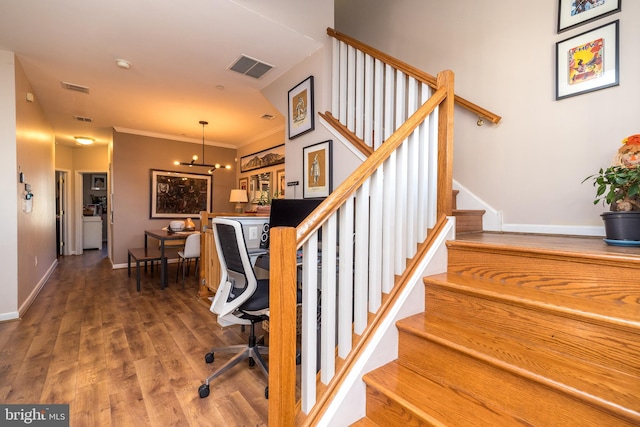 stairway featuring hardwood / wood-style flooring, a notable chandelier, and crown molding