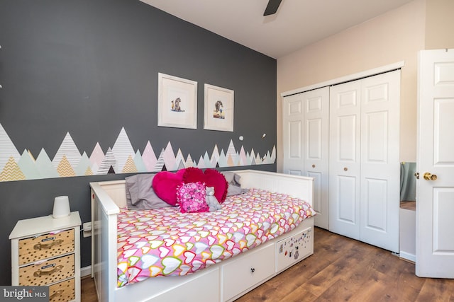 bedroom with ceiling fan, dark wood-type flooring, and a closet