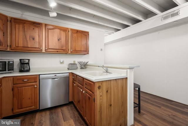 kitchen featuring appliances with stainless steel finishes, dark hardwood / wood-style flooring, sink, a breakfast bar, and kitchen peninsula