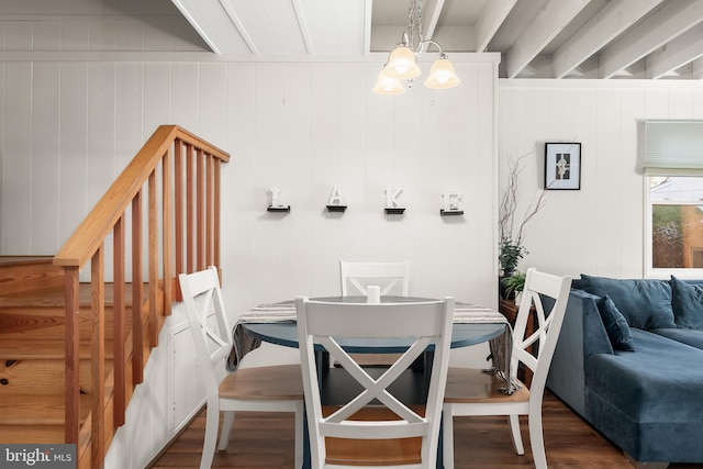 dining area with dark wood-type flooring, wooden walls, and beam ceiling