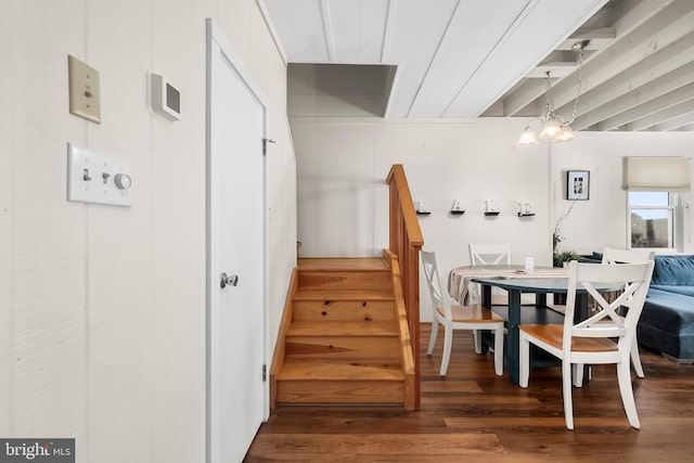 dining room with wood walls, dark hardwood / wood-style flooring, and a notable chandelier