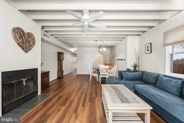 living room with beamed ceiling, dark hardwood / wood-style floors, wooden walls, and ceiling fan