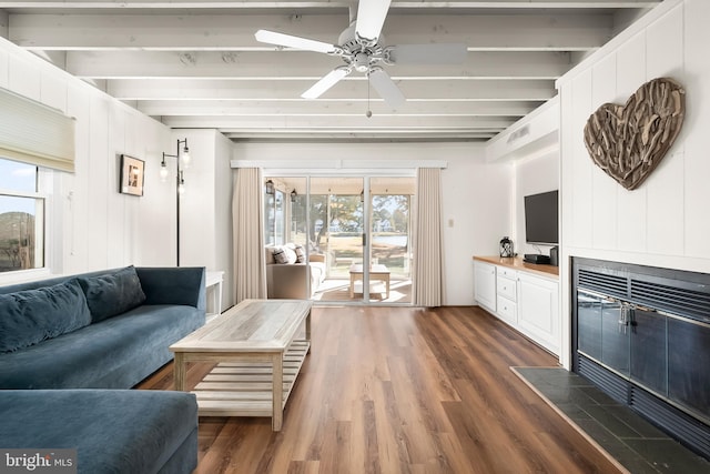 living room featuring dark wood-type flooring, beamed ceiling, and ceiling fan