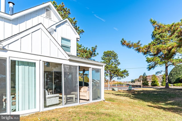 rear view of house with a sunroom and a yard