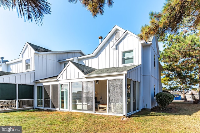 rear view of house with a sunroom and a lawn