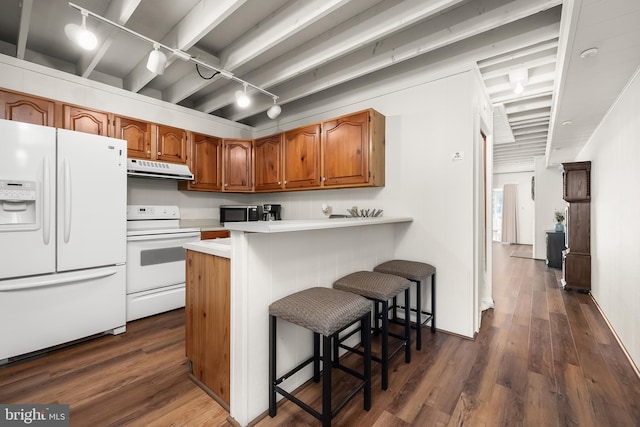 kitchen with kitchen peninsula, track lighting, dark hardwood / wood-style floors, a breakfast bar, and white appliances