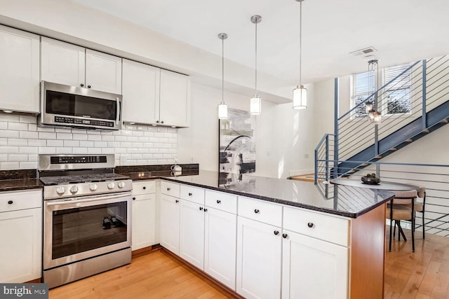 kitchen featuring white cabinetry, stainless steel appliances, and decorative light fixtures