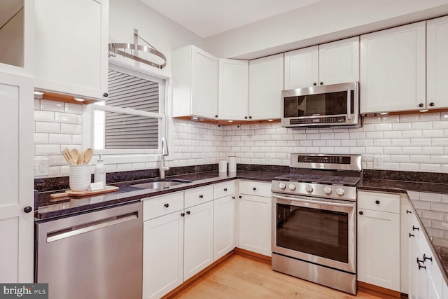 kitchen with decorative backsplash, appliances with stainless steel finishes, light wood-type flooring, sink, and white cabinets