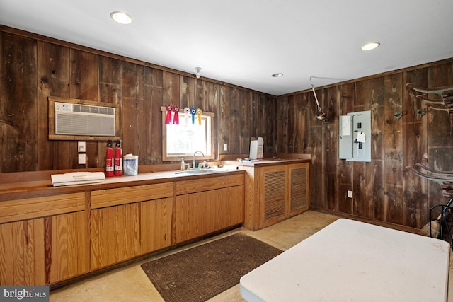 kitchen with pendant lighting, a wall unit AC, wooden walls, and sink