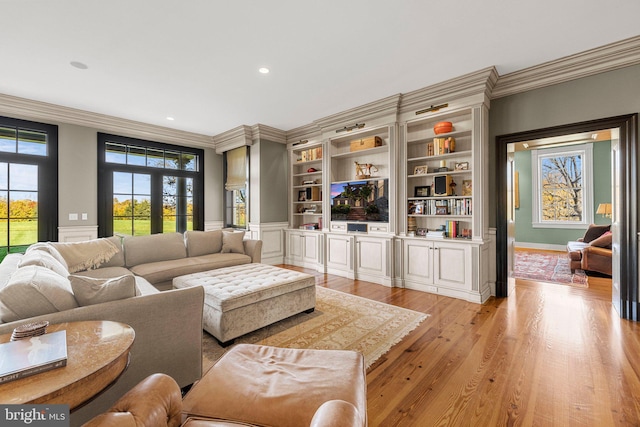 living room with built in shelves, light hardwood / wood-style floors, and ornamental molding