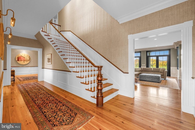 stairway with french doors, wood-type flooring, and ornamental molding