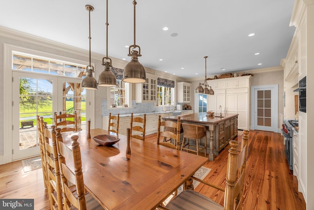 dining space with sink, light wood-type flooring, crown molding, and french doors