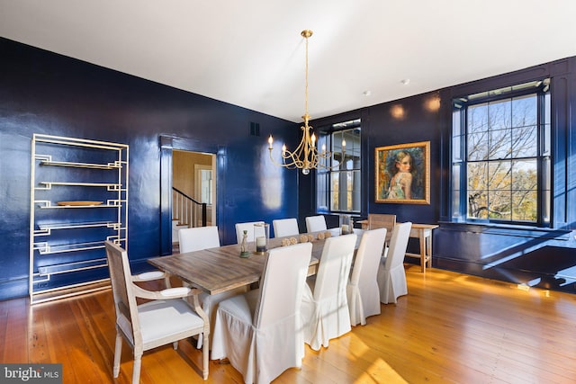 dining space with wood-type flooring and an inviting chandelier