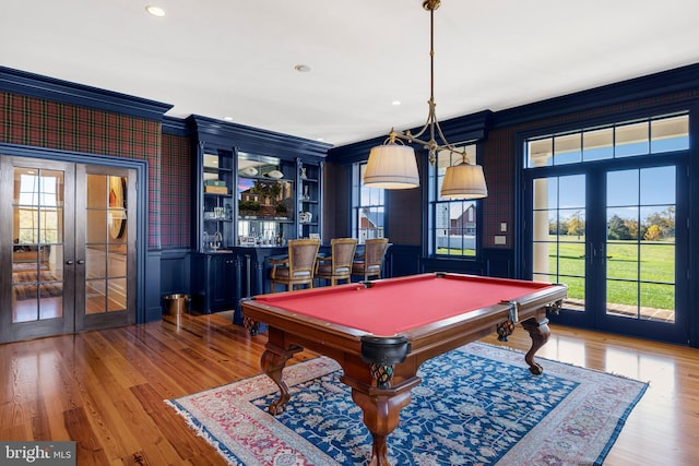 game room with french doors, pool table, light hardwood / wood-style flooring, bar area, and ornamental molding