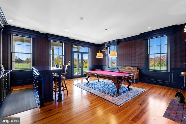 recreation room featuring light wood-type flooring, crown molding, and a healthy amount of sunlight