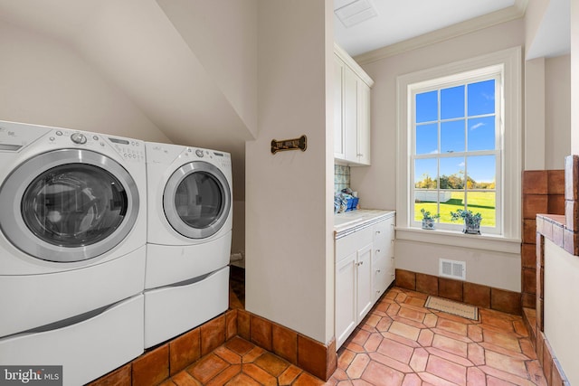 clothes washing area featuring cabinets, independent washer and dryer, and crown molding