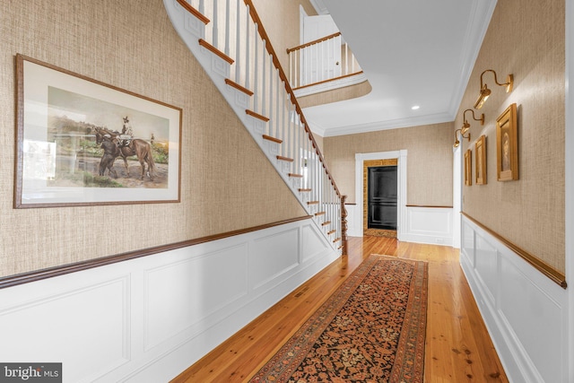 hall with light hardwood / wood-style floors and ornamental molding