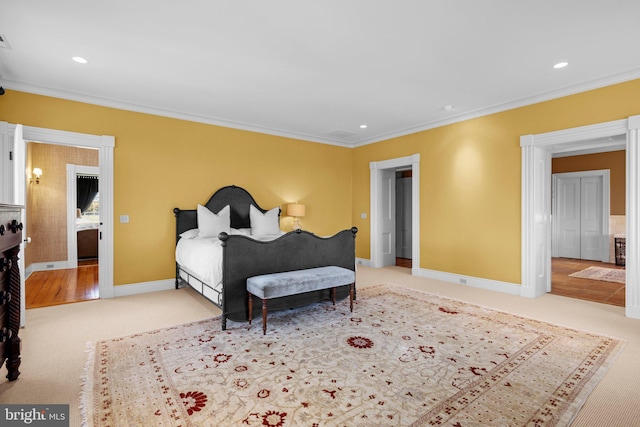 bedroom with ensuite bath, crown molding, and light carpet