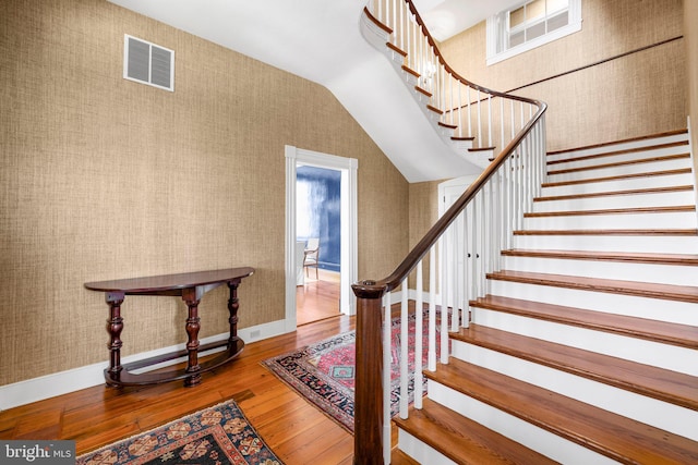 stairs with hardwood / wood-style flooring and lofted ceiling