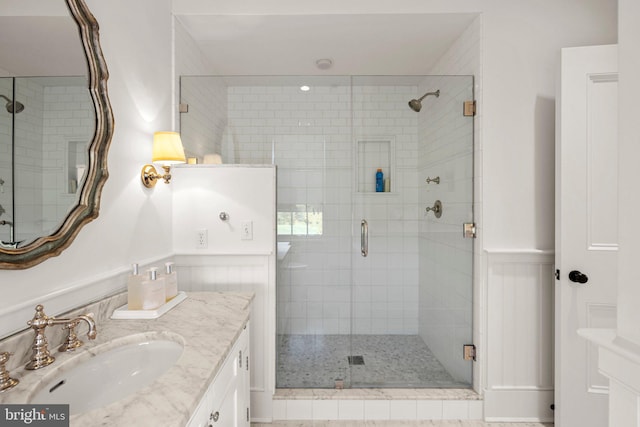 bathroom featuring a shower with door and vanity