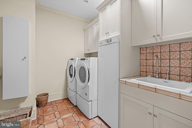 clothes washing area with washer and clothes dryer, cabinets, sink, ornamental molding, and light tile patterned floors