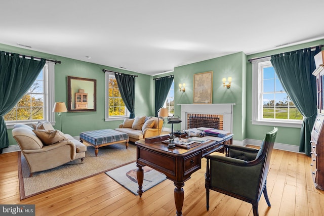 living room with a healthy amount of sunlight, a fireplace, and light hardwood / wood-style flooring