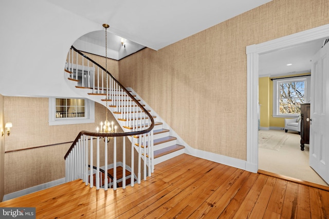 stairway featuring hardwood / wood-style flooring and a notable chandelier