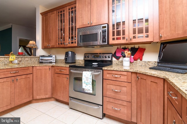 kitchen with stainless steel appliances, light tile patterned flooring, and light stone counters