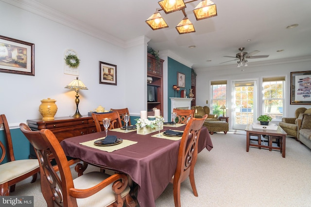 carpeted dining room with ceiling fan and crown molding