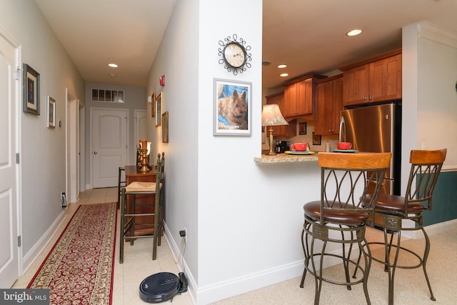 kitchen featuring kitchen peninsula, a kitchen bar, and stainless steel fridge