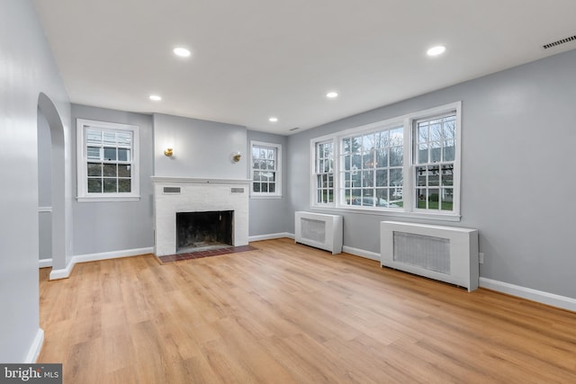 unfurnished living room featuring radiator, plenty of natural light, and light hardwood / wood-style floors