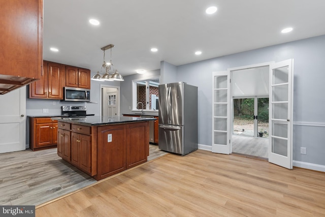 kitchen with pendant lighting, light hardwood / wood-style flooring, stainless steel appliances, a kitchen island, and french doors