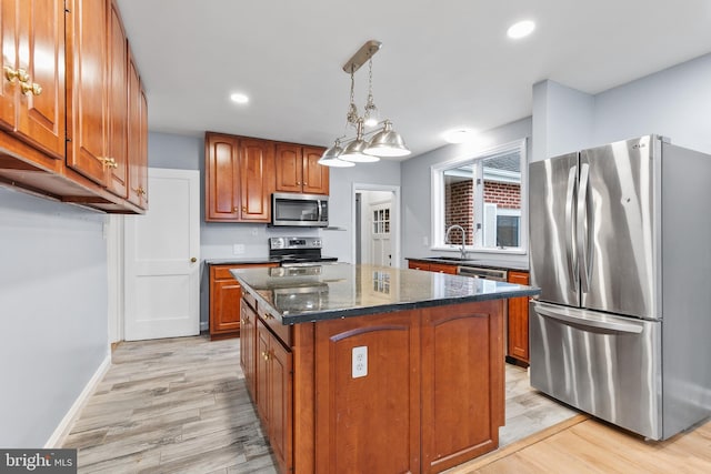 kitchen with pendant lighting, sink, dark stone countertops, stainless steel appliances, and a kitchen island