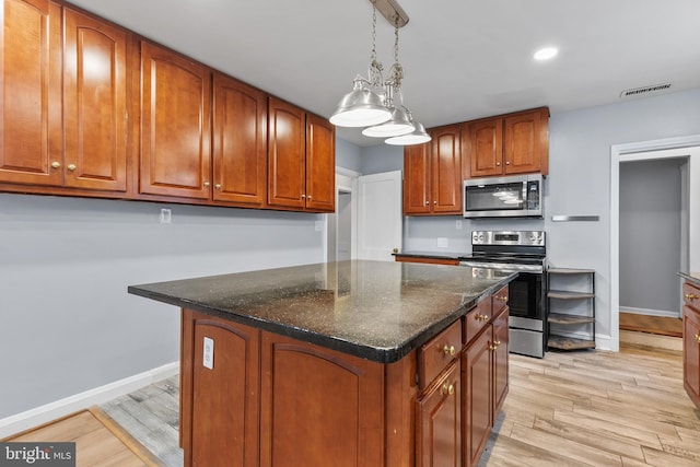 kitchen with a kitchen island, dark stone countertops, hanging light fixtures, light hardwood / wood-style floors, and stainless steel appliances