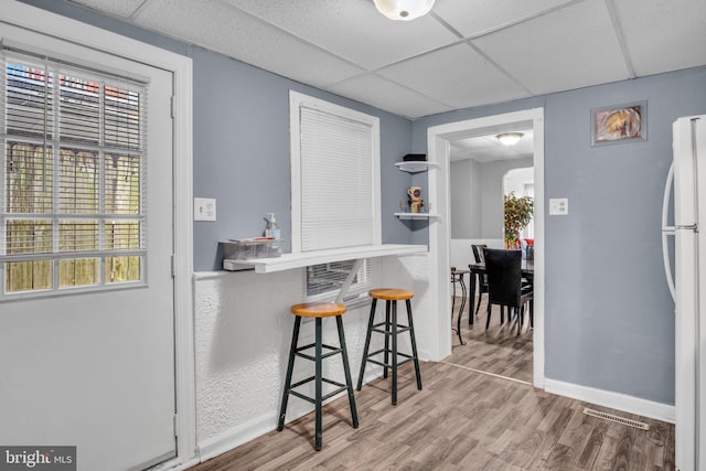 kitchen featuring a drop ceiling, white refrigerator, and wood-type flooring