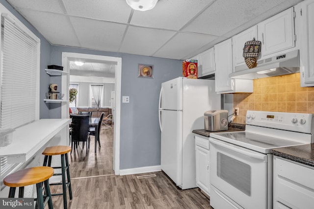 kitchen with ventilation hood, wood-type flooring, white cabinetry, a drop ceiling, and white appliances