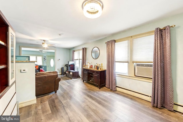 living room featuring ceiling fan, baseboard heating, wood-type flooring, and cooling unit