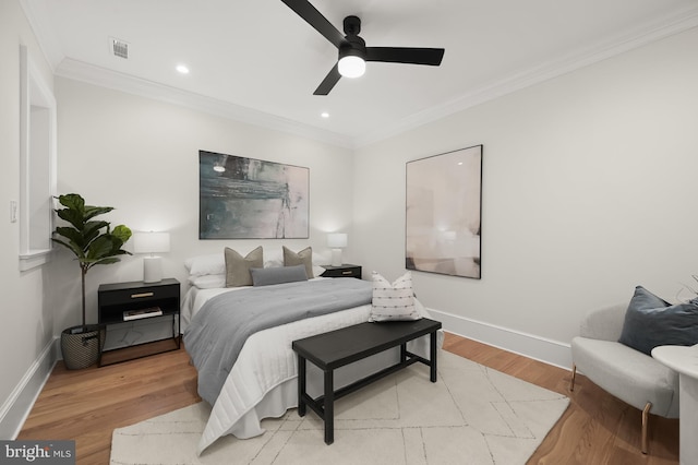 bedroom featuring light wood-type flooring, ceiling fan, and crown molding