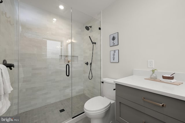 bathroom featuring toilet, a shower with door, and vanity