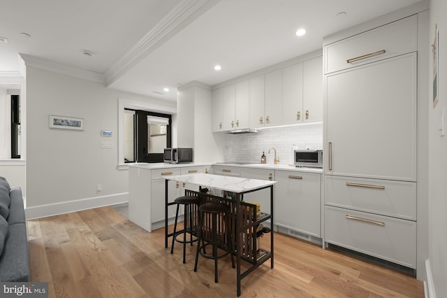 kitchen with tasteful backsplash, white cabinetry, a breakfast bar area, and a center island