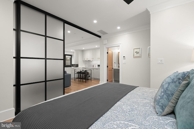 bedroom with ensuite bathroom, ornamental molding, and light hardwood / wood-style flooring