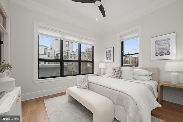 bedroom featuring ceiling fan, crown molding, multiple windows, and hardwood / wood-style flooring