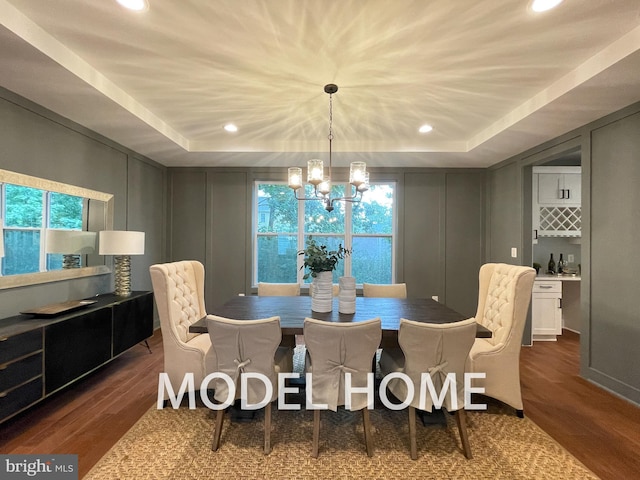 dining area featuring a notable chandelier, dark wood-type flooring, and a tray ceiling