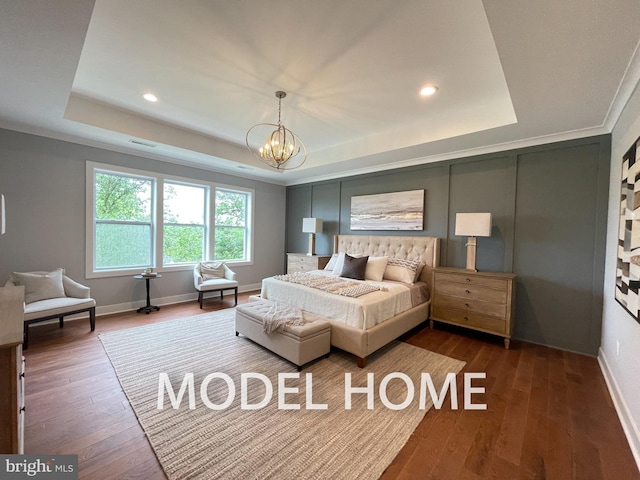 bedroom featuring dark hardwood / wood-style floors, ornamental molding, a raised ceiling, and a notable chandelier